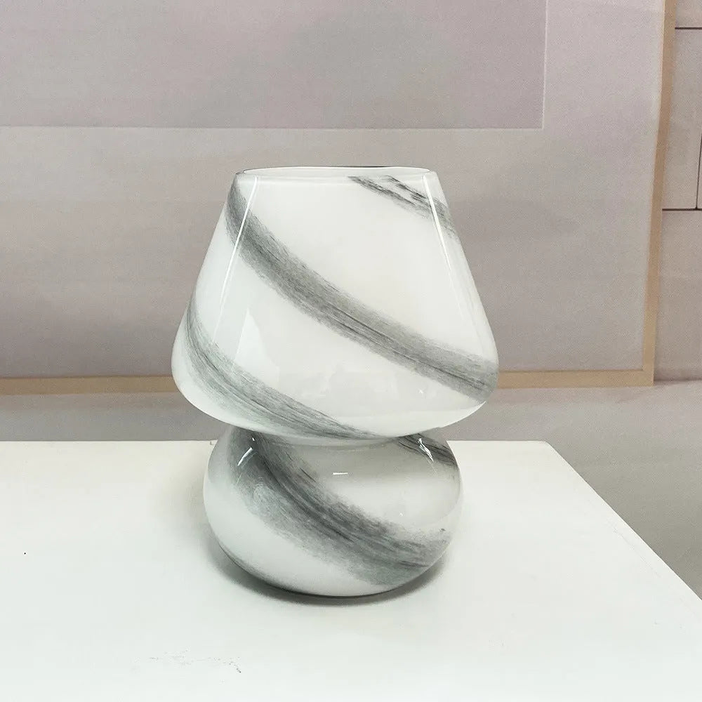 Handmade glass mushroom table lamp in Earth colour on a wooden bedside table with a soft glow