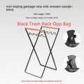 Outdoor black iron folding garbage storage hanger with wooden handle holding a bin bag.