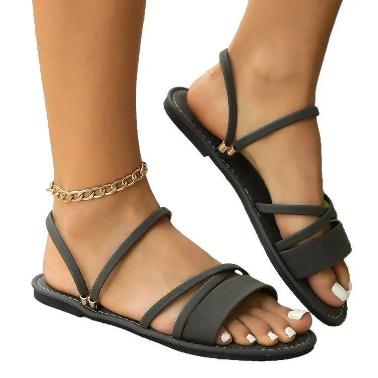 Women's black flip-toe buckle sandal with cross strap on flat rubber sole