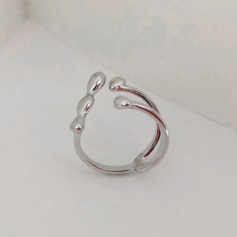 Gold tone brass ring with open circle design and central sphere on a person's finger.