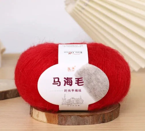 A ball of mohair yarn in a selected colour next to a hand-woven scarf example, showcasing the DIY kit.