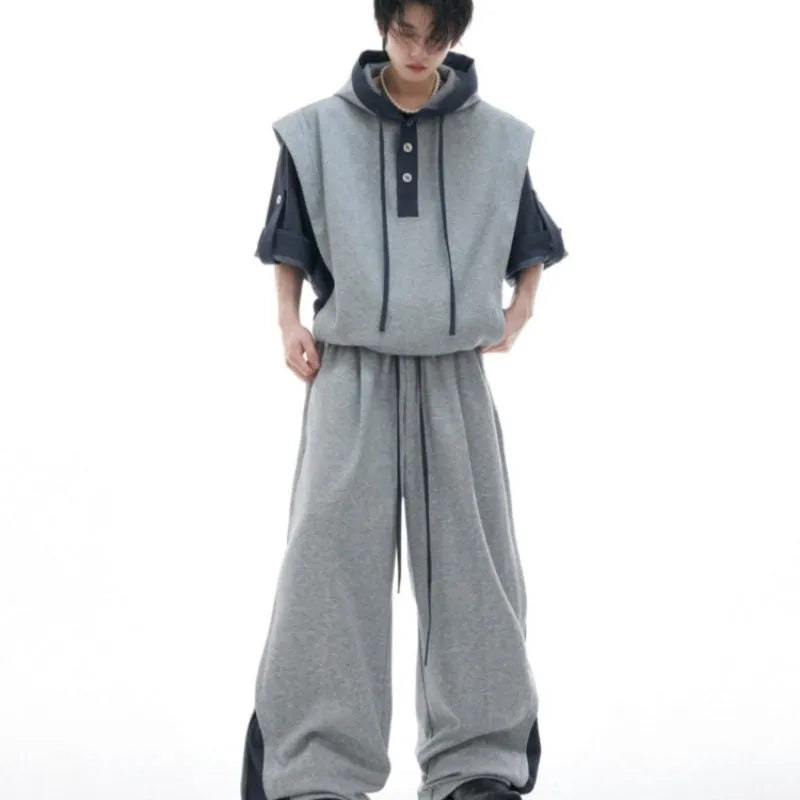 Man wearing a black hooded short sleeve sports jacket with textured stitching and matching full-length trousers.
