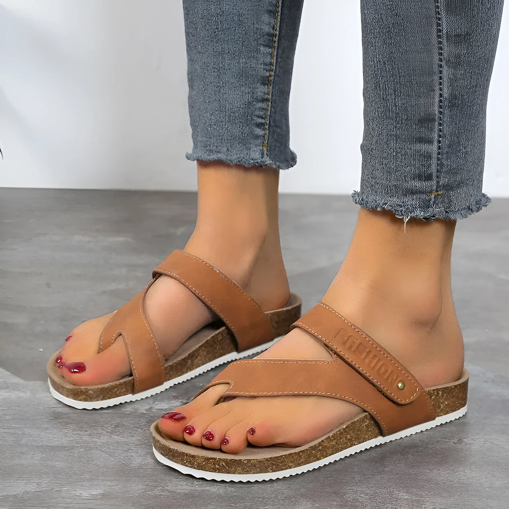 Flat toe ring flip-flops with a thick foam sole in a solid blue colour on a sandy beach.