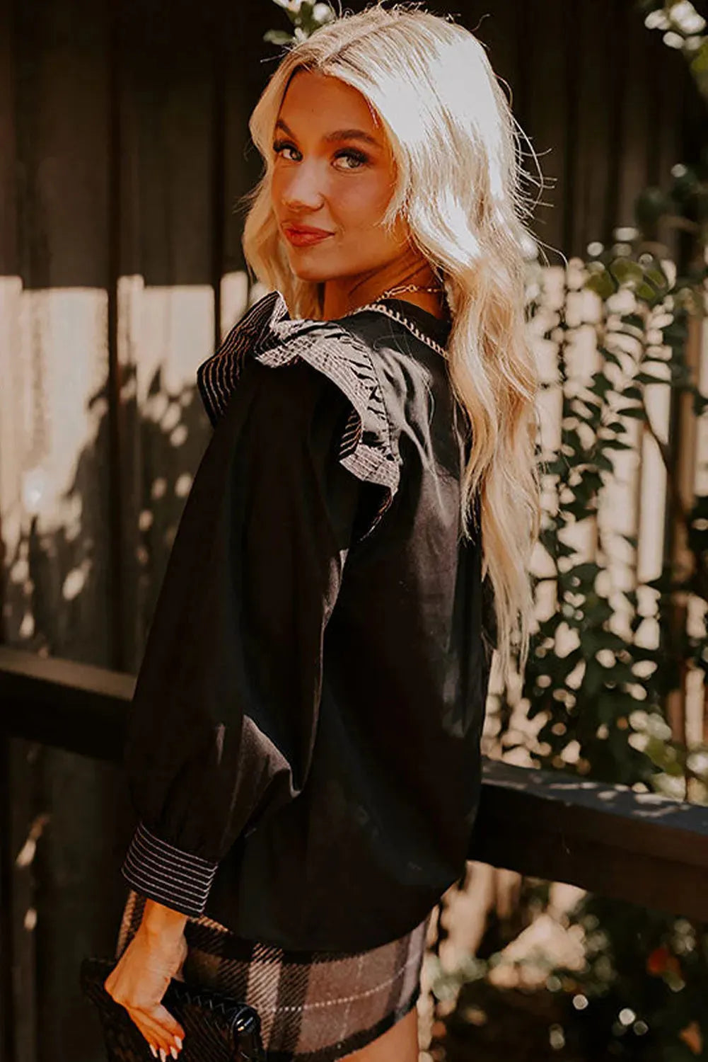 Black women's blouse with V-neck collar, long ruffle sleeves, and contrast colour stitching.