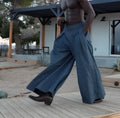 Grey men's wide-leg trousers with front waist pleats and an elasticated waistband.