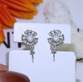 Baroque style sterling silver flower earrings with detailed scrollwork and a ring placed on the central stem.
