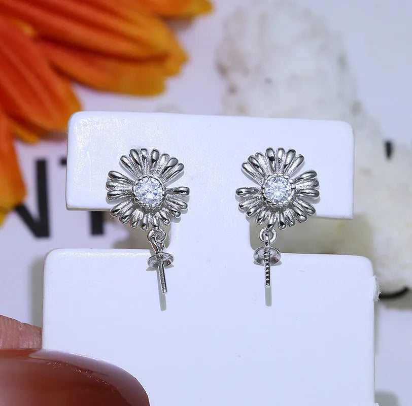 Baroque style sterling silver flower earrings with detailed scrollwork and a ring placed on the central stem.