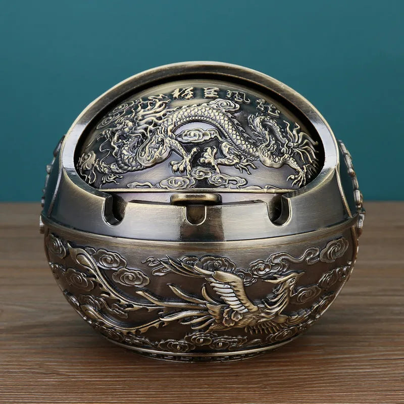 Alloy decorative ashtray in bronze with ornate peacock motif and cigarette extinguishing slot.