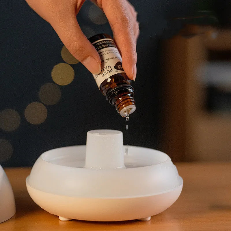 Black and white USB humidifier diffuser with glowing flame effect light on a wooden table.