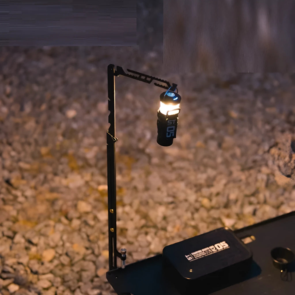 Black stainless steel telescopic lamp holder with gear adjustment mechanism on a desk edge.