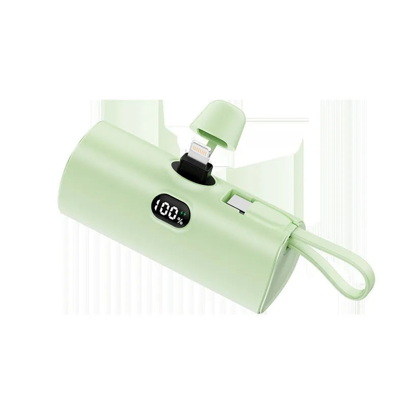 Compact capsule-shaped wireless power bank with a UK plug and digital display, shown in pink.