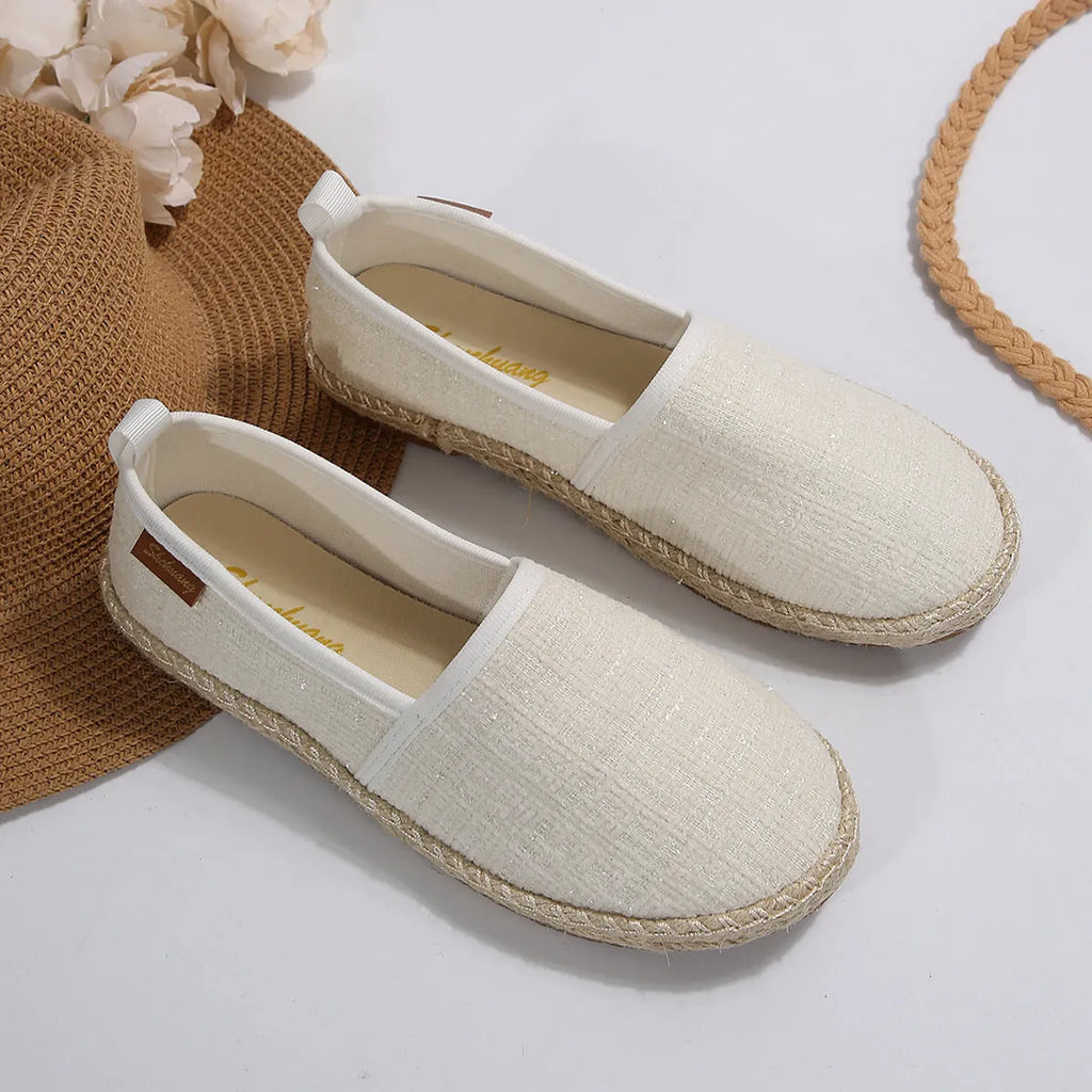 Casual beige canvas fisherman shoes with a rope sole and flat heel on a plain background.
