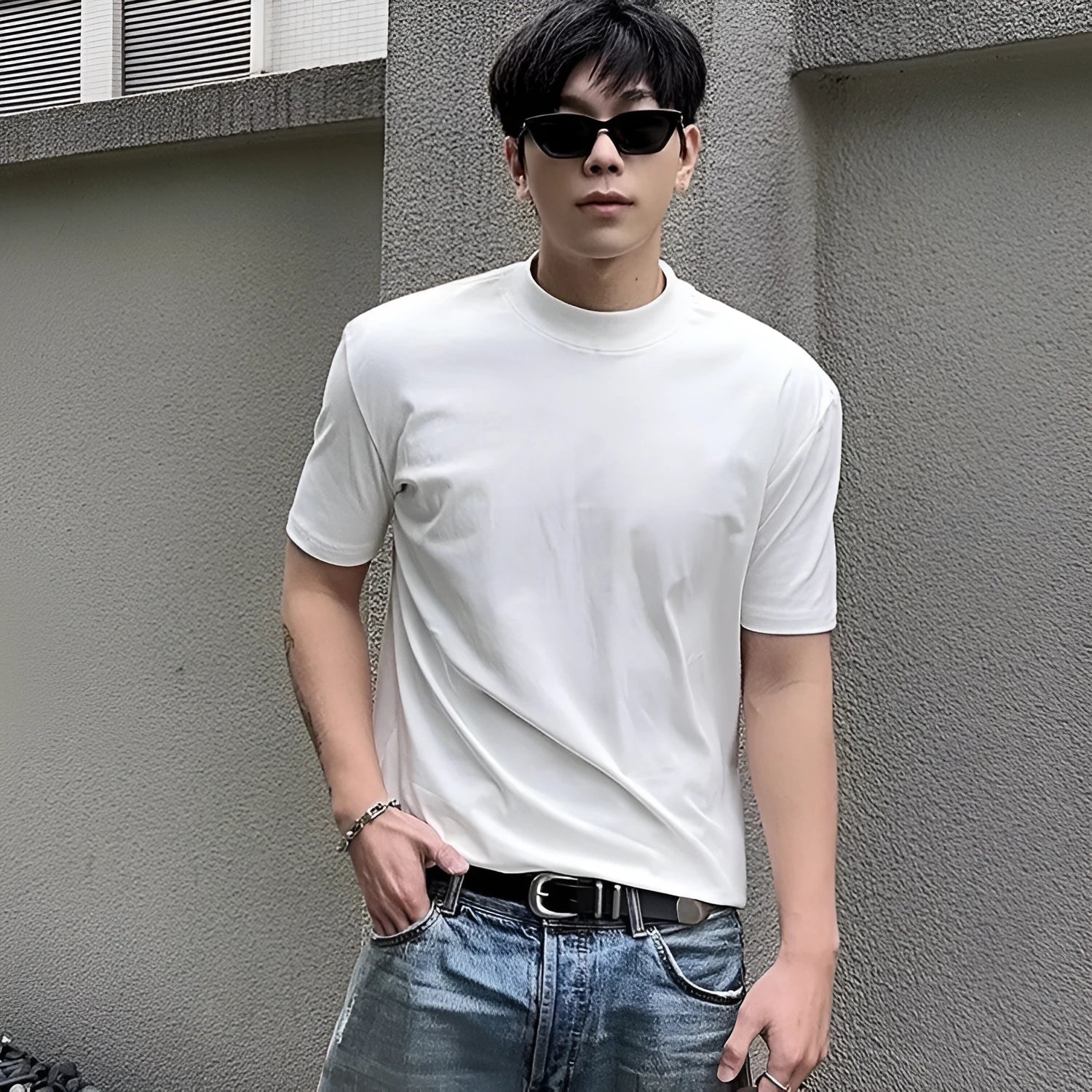 Man wearing a loose-fit grey cotton short-sleeve t-shirt with a half turtleneck cuff shoulder detail.