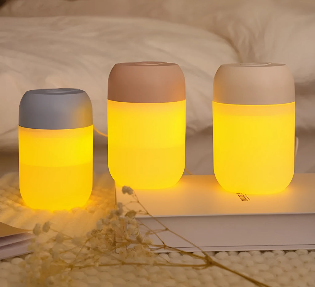 White cylindrical mini USB humidifier on a wooden desk next to a laptop.