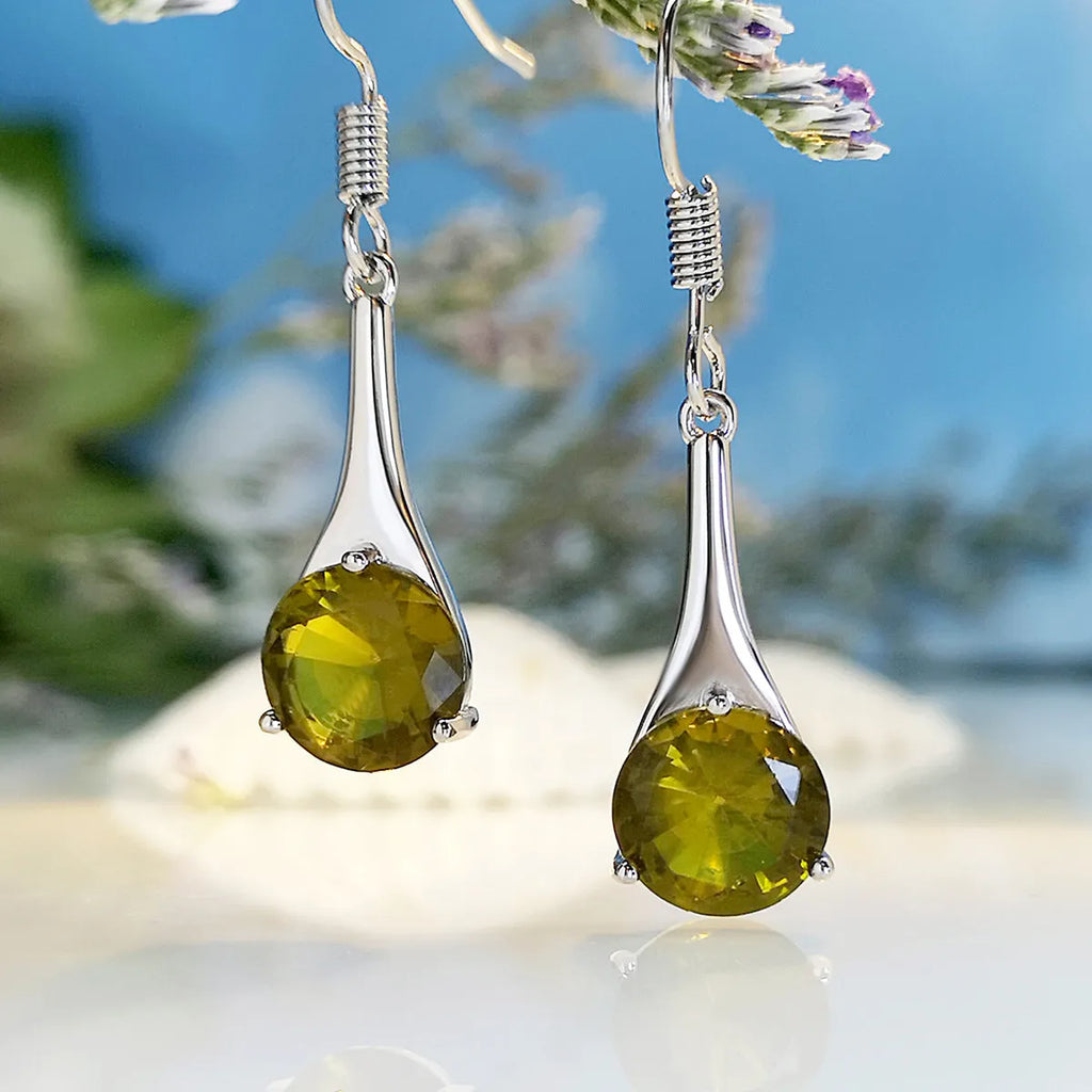 Olive green topaz coloured drop-shaped fashion earrings with a retro style on a white background.