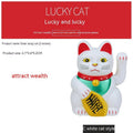 Yellow solar Maneki Neko lucky cat waving its arm on a car dashboard.