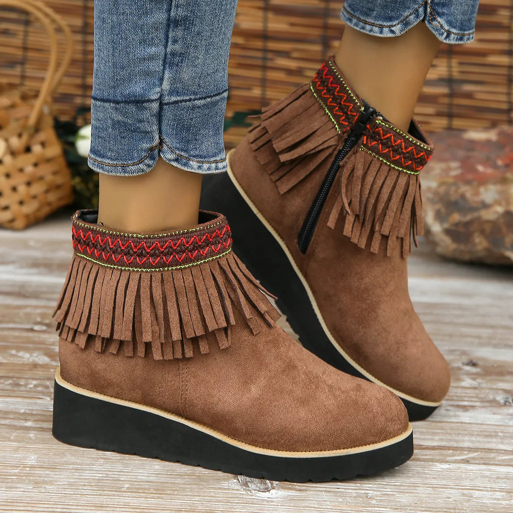 Women's black suede wedge bootie with a thick sole, side zipper, and tassel detail.