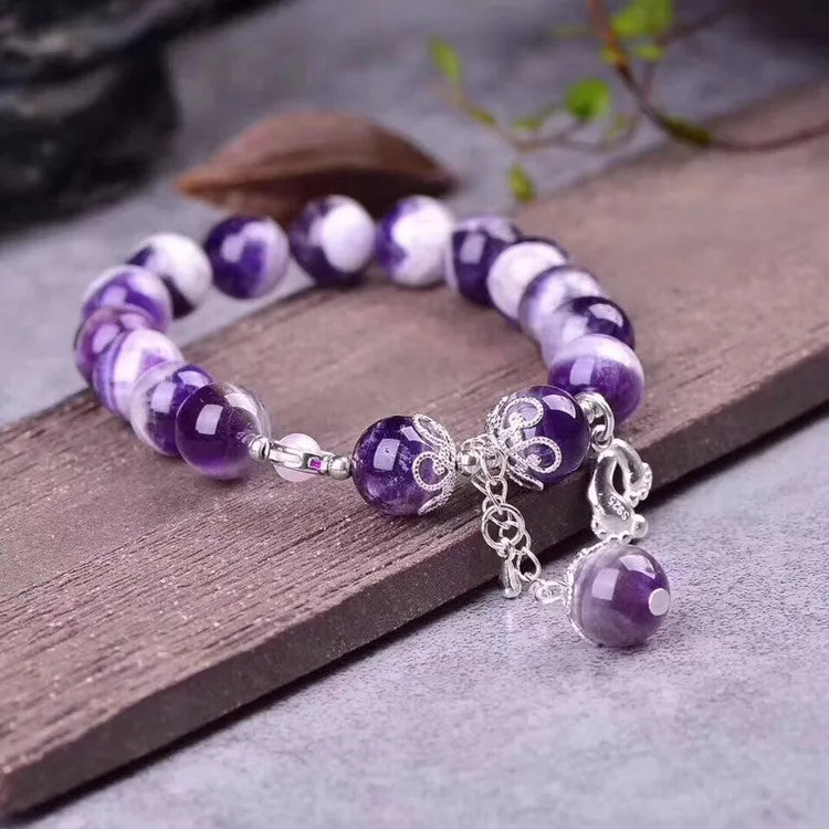 Women's amethyst bracelet with 10mm round purple beads on a wrist.