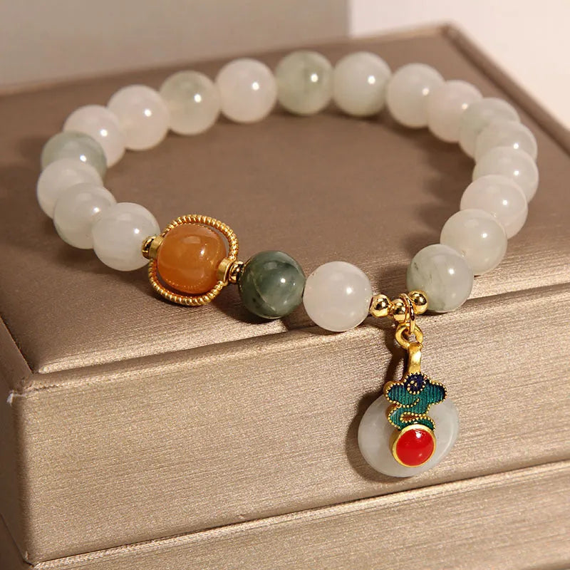 Women's ice jade bracelet with Xiangyun peace buckle and pearl details on a wrist.