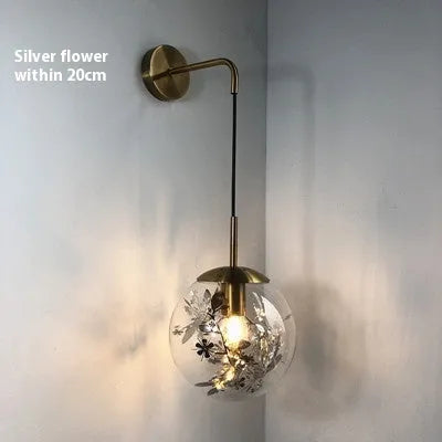 Modern simple glass bedside wall lamp in silver or gold finish on a white wall.