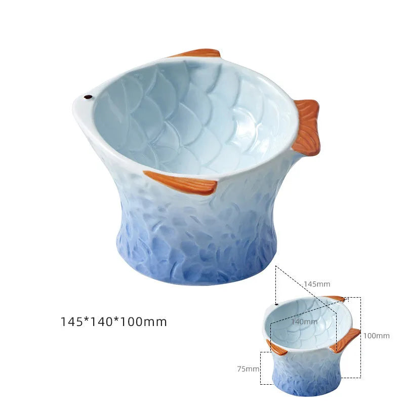 Set of blue fish-shaped ceramic cat bowls with a tilted angle on a wooden surface.