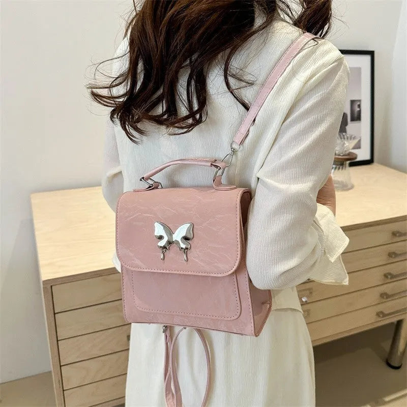 Preppy style white PU women's backpack with a black detachable bow decoration and visible stitching.