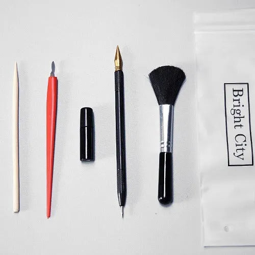 Scratch painting art tool set with healing pen, brushes, and scraper on white card paper.