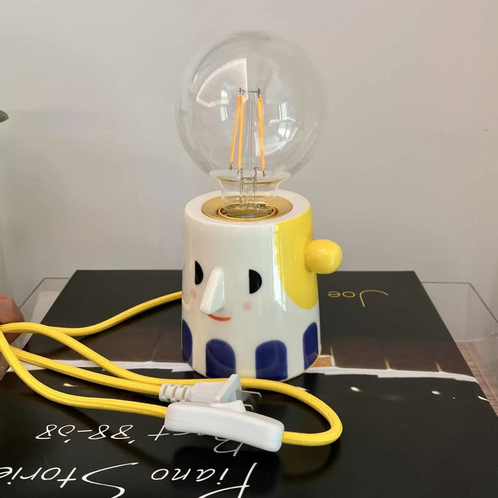 Handmade ceramic bedside lamp with a white ball headlight on a wooden table.
