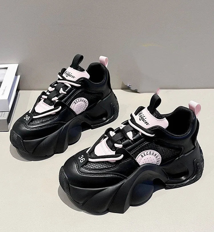 Women's pink sneakers with a cross strap and thick sole on a neutral background.