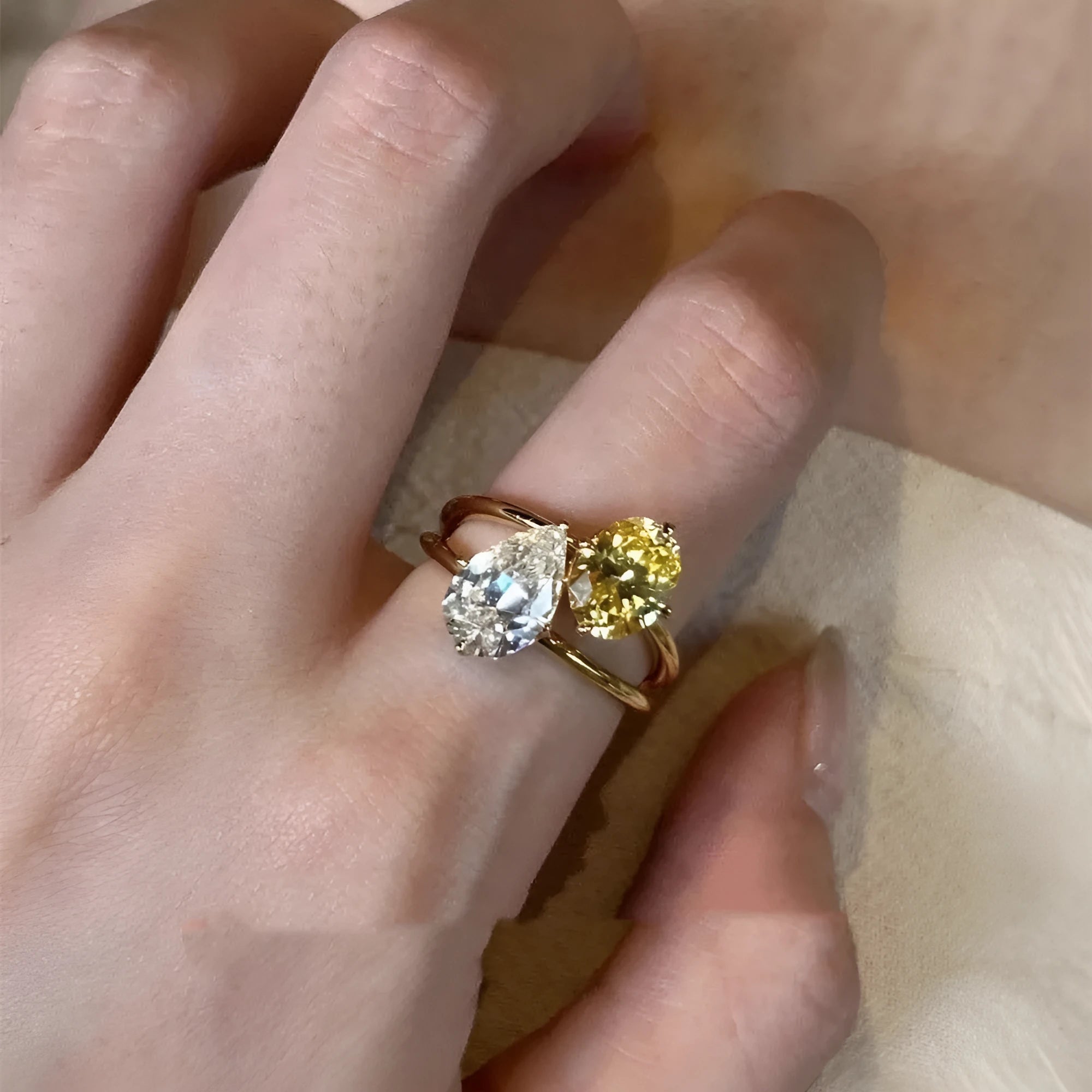 Geometric open copper ring with blue water drop and two clear crystals on a woman's hand.