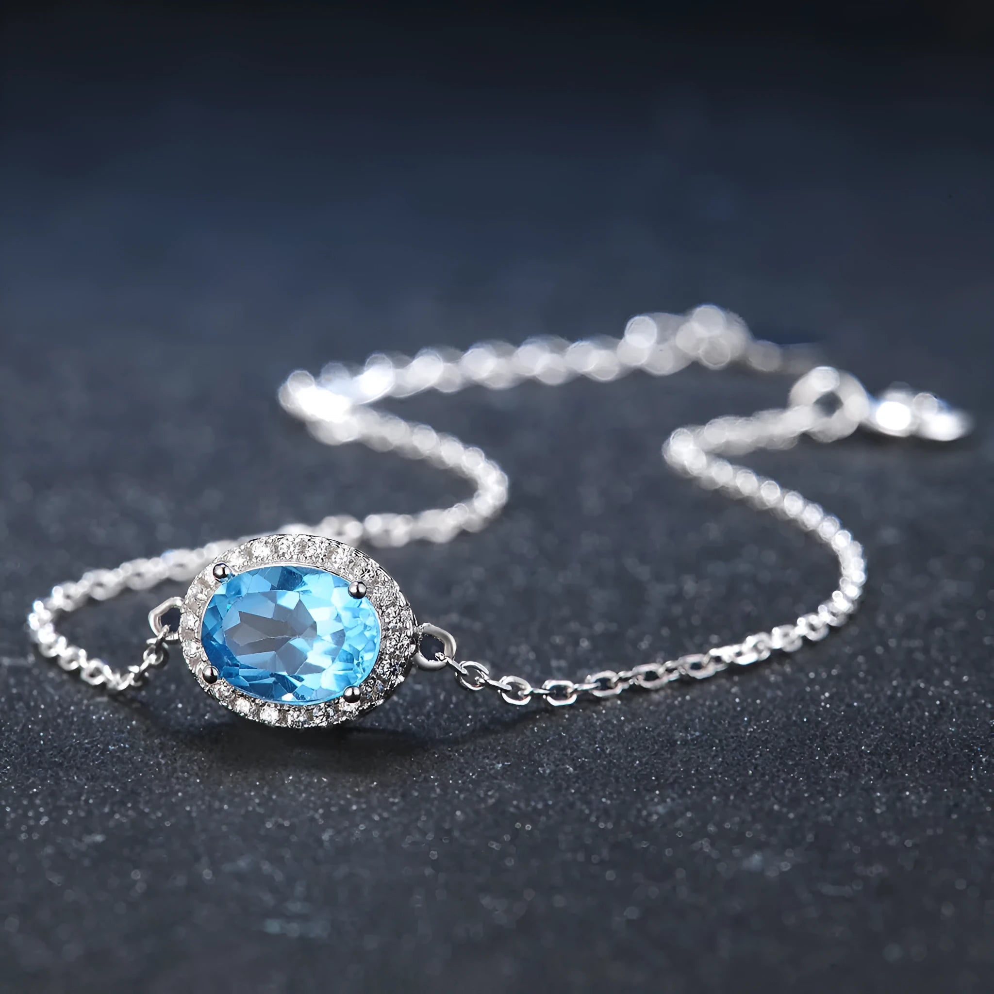 Women's four-piece sterling silver jewellery set with blue topaz gems, showing geometric earrings, ring, pendant and necklace.