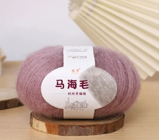 A ball of mohair yarn in a selected colour next to a hand-woven scarf example, showcasing the DIY kit.