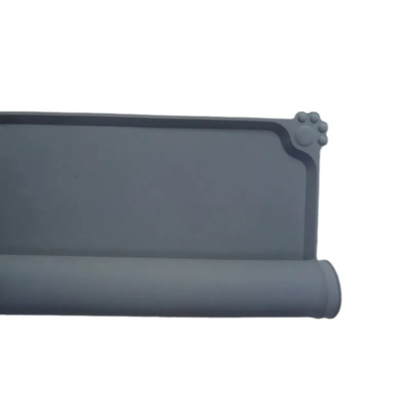 Grey silicone pet food mat with raised edges on a tile floor