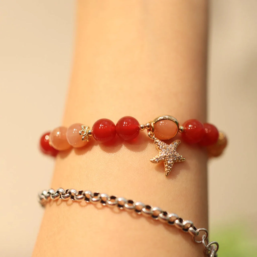 Handmade red agate bracelet with 8mm beads, star and xiangyun patterns, on a wrist.