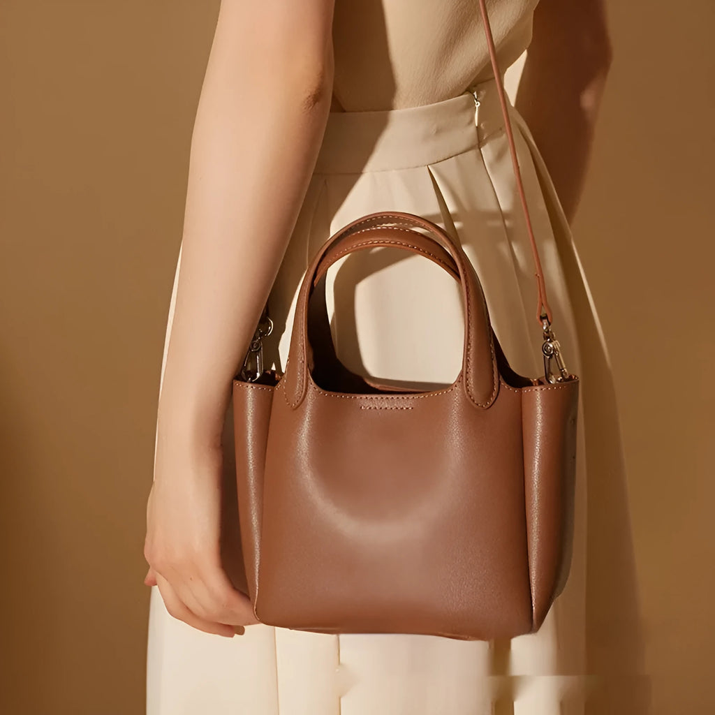 Genuine cattlehide leather retro crossbody bucket bag in black showing external slit pocket and sewing thread detail.