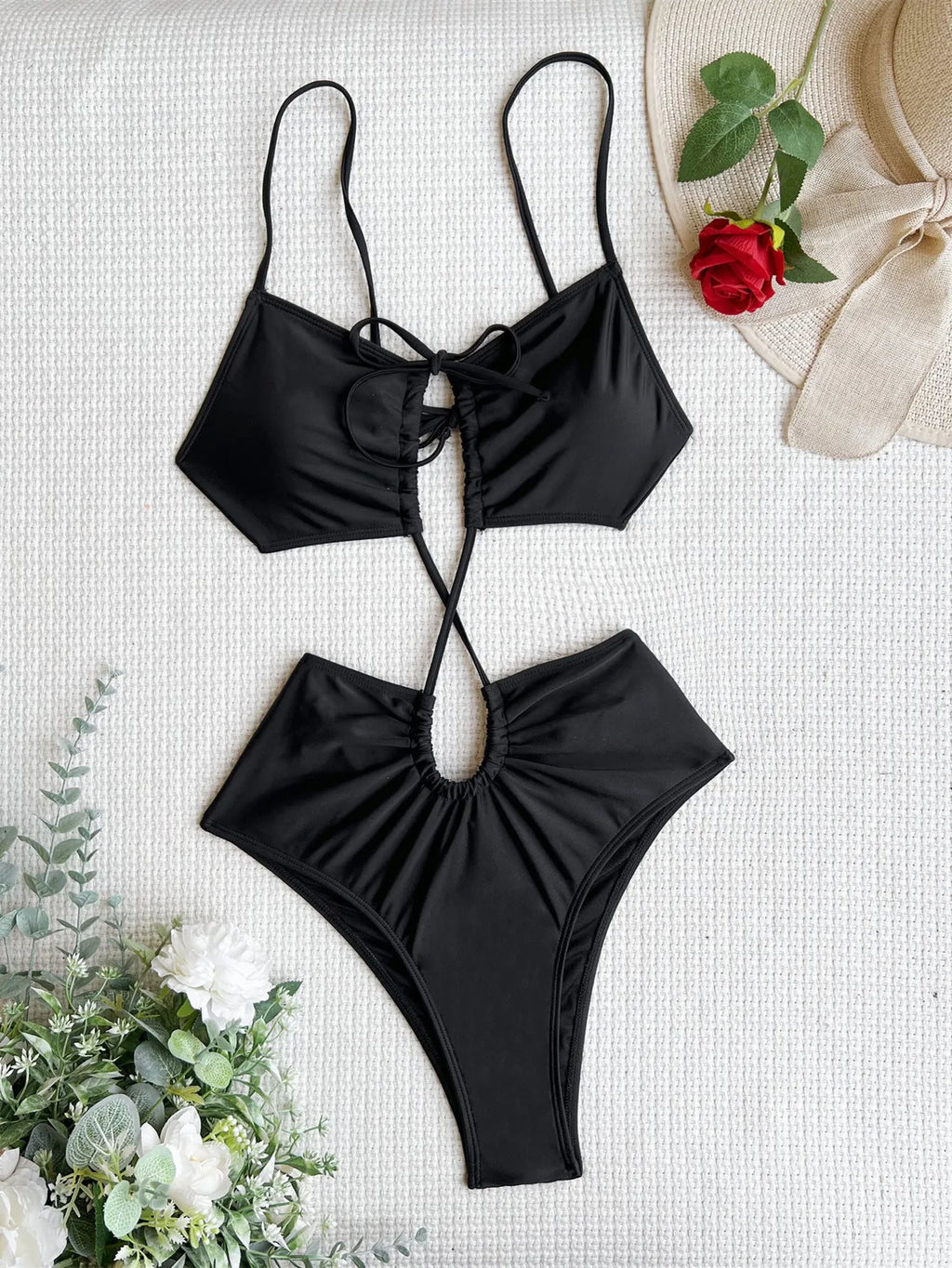 Women's sleeveless hollow back one-piece swimsuit in black, shown on a model from the back.
