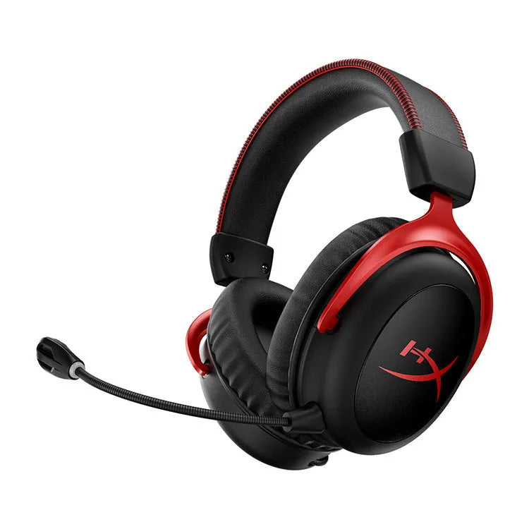 Black and red wired gaming headset with detachable microphone and separate USB sound card remote control on a desk.