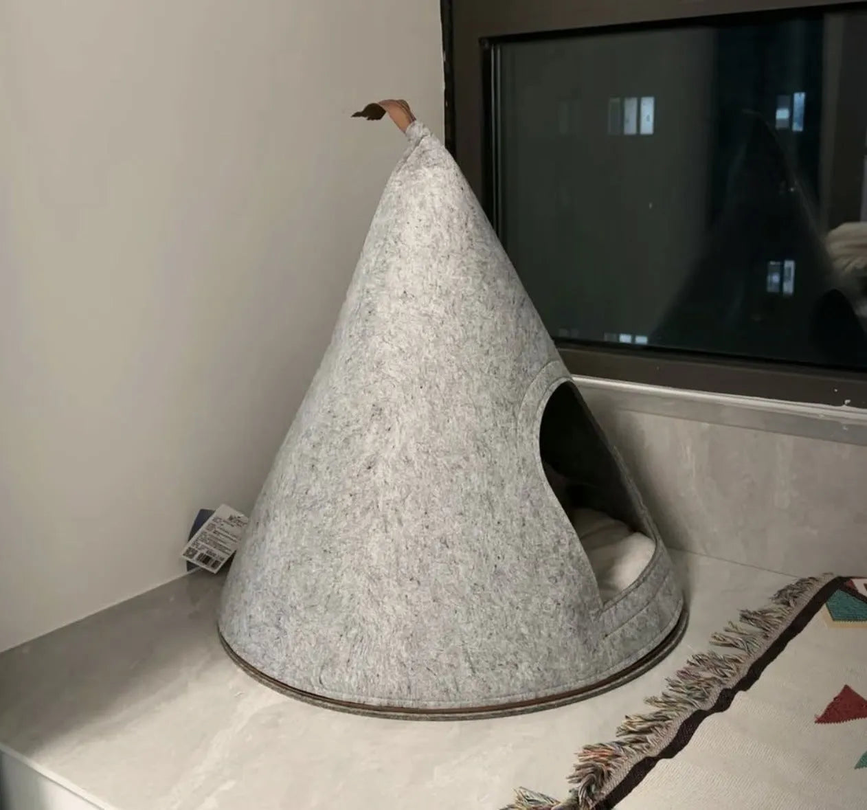 Grey cone-shaped felt cat house with circular opening for indoor cat sleeping