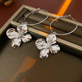 Close-up of silver needle style metal flower earrings with a geometric design in a gold or silver finish.