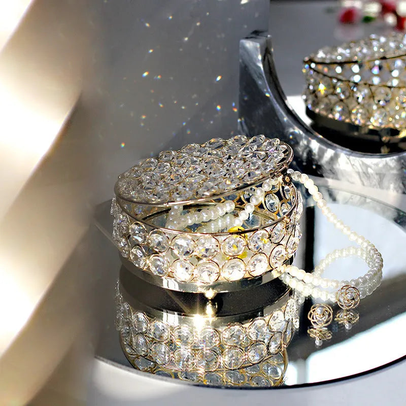 Crystal clear glass jewelry box with French gold metal frame on a table.
