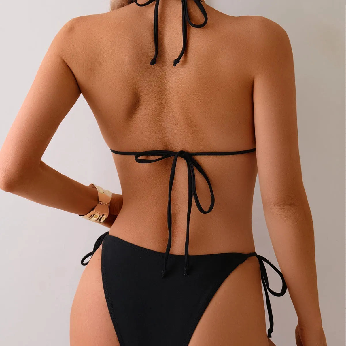 Black women's bikini swimsuit with metal bead decoration and split design.