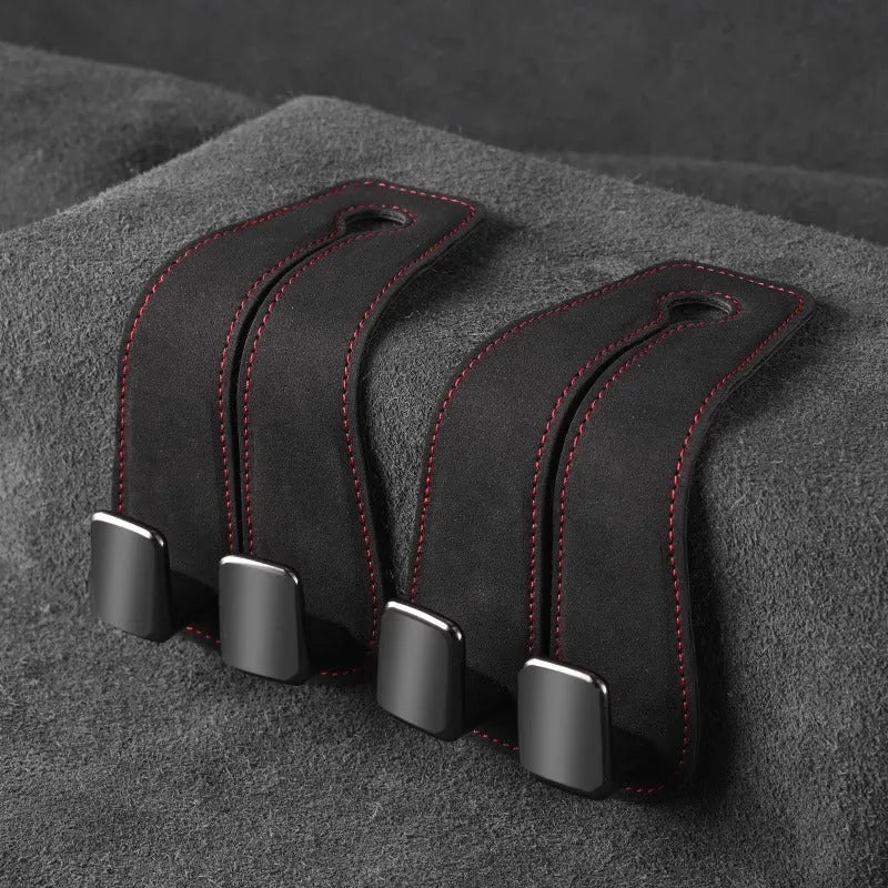 Alloy car seat hook clipped to headrest post in black, showing flip-down design for bag storage.