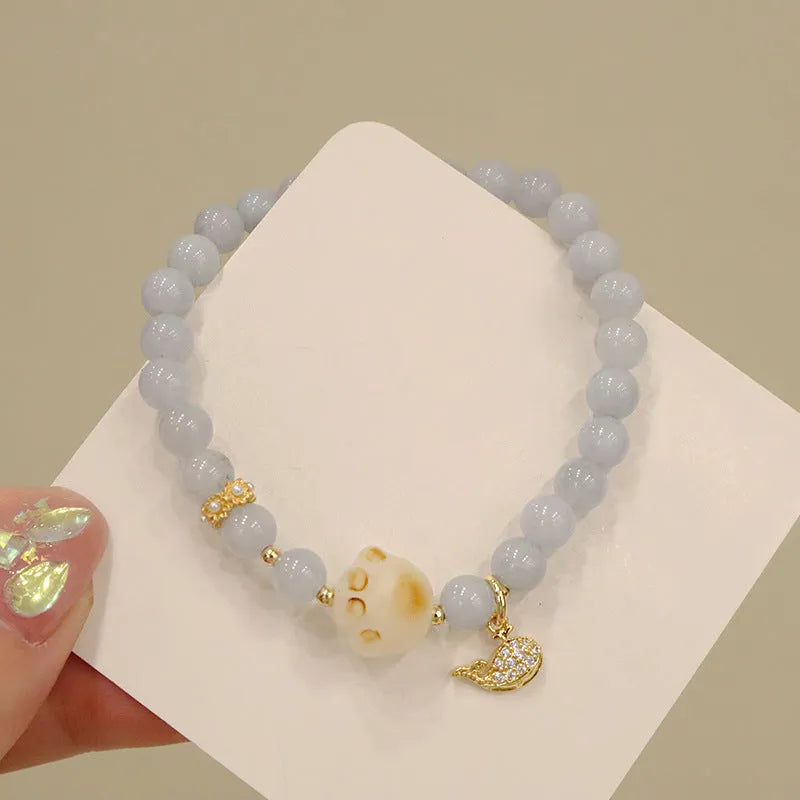 Gold plated bracelet with a detailed artificial crystal charm pendant on a woman's wrist.