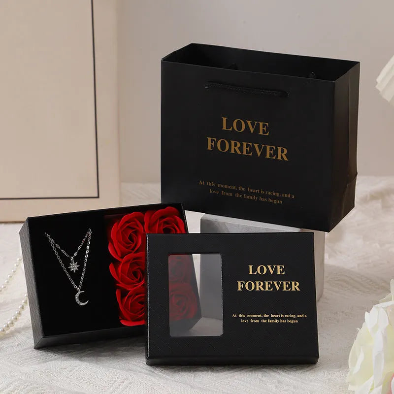 Red Korean-style gift box open to show six pink soap flowers, with a matching red handbag beside it.