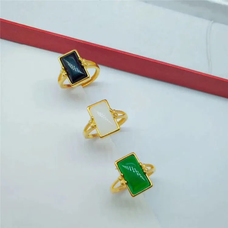 Adjustable brass gold-plated ring with a coloured gemstone inlay on a finger.
