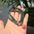 Close-up of a women's tourmaline bracelet with blue water abacus beads and emerald beads in a three-ring design.