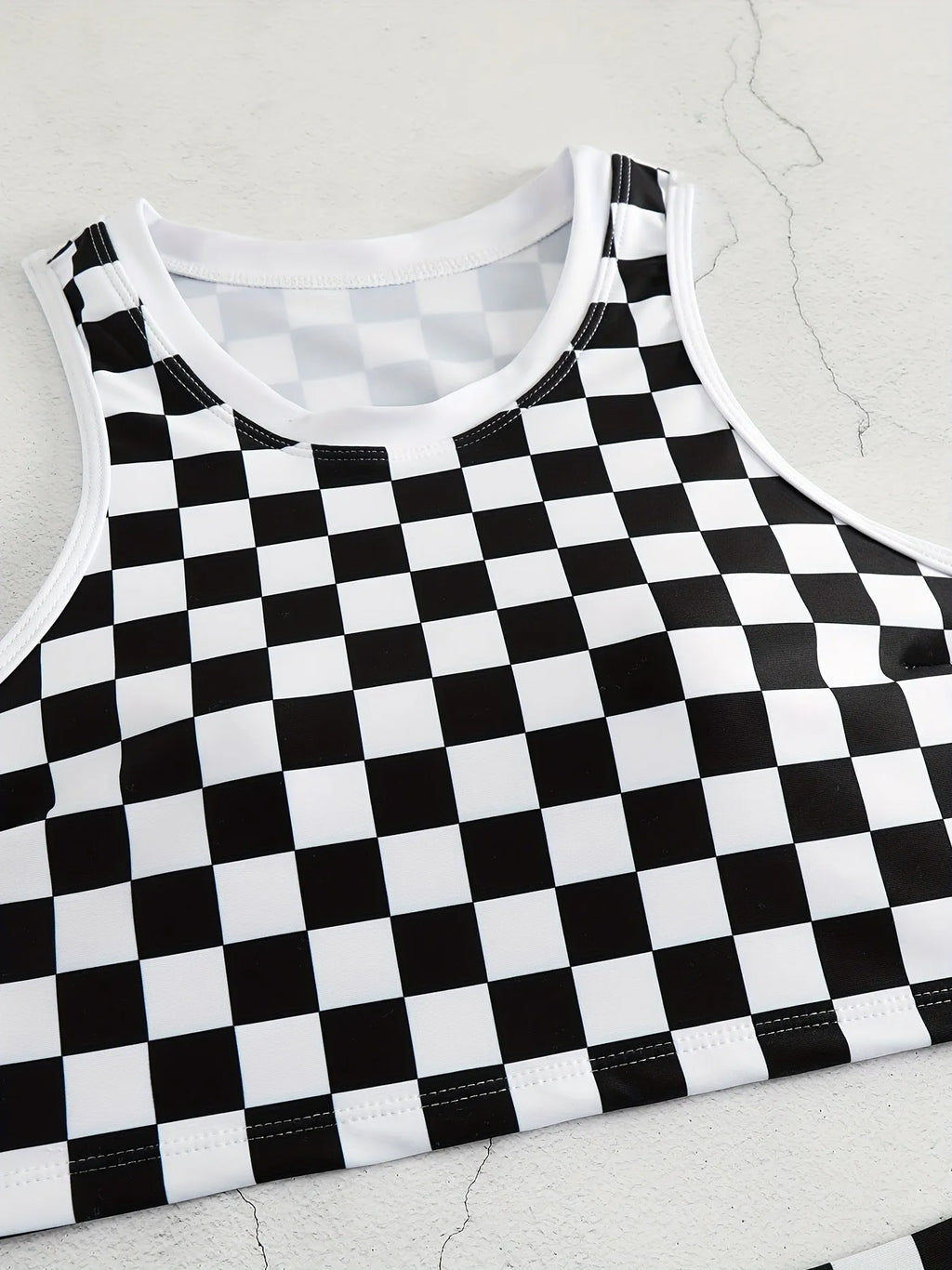 Women's backless racing swimsuit with shoulder suspender strap in black and white chessboard pattern