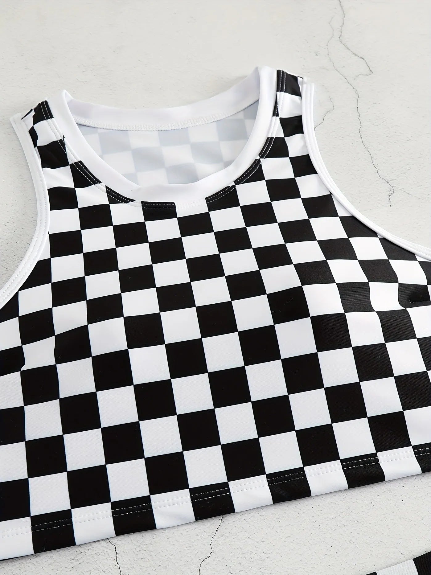 Women's backless racing swimsuit with shoulder suspender strap in black and white chessboard pattern