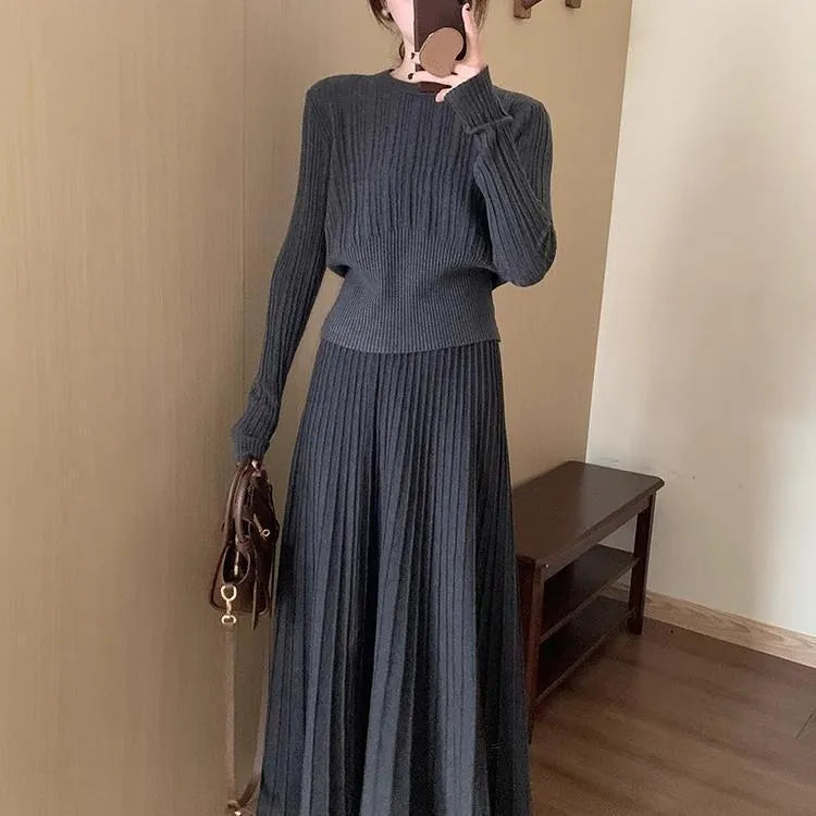 Dark grey knitted women's sweater and skirt set with a raised 3D pattern, laid flat.