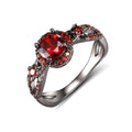 Black gold plated copper ring with round red zircon stone and wave-shaped band on finger